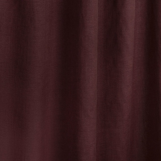 Deep Bordeaux red woven textile falling in softly shadowed vertical folds