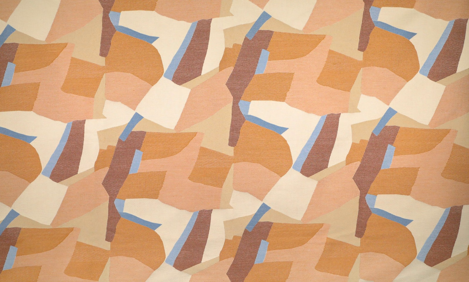 Terracotta abstract patchwork fabric with peach, cream, tan, blue and plum-brown geometric shapes