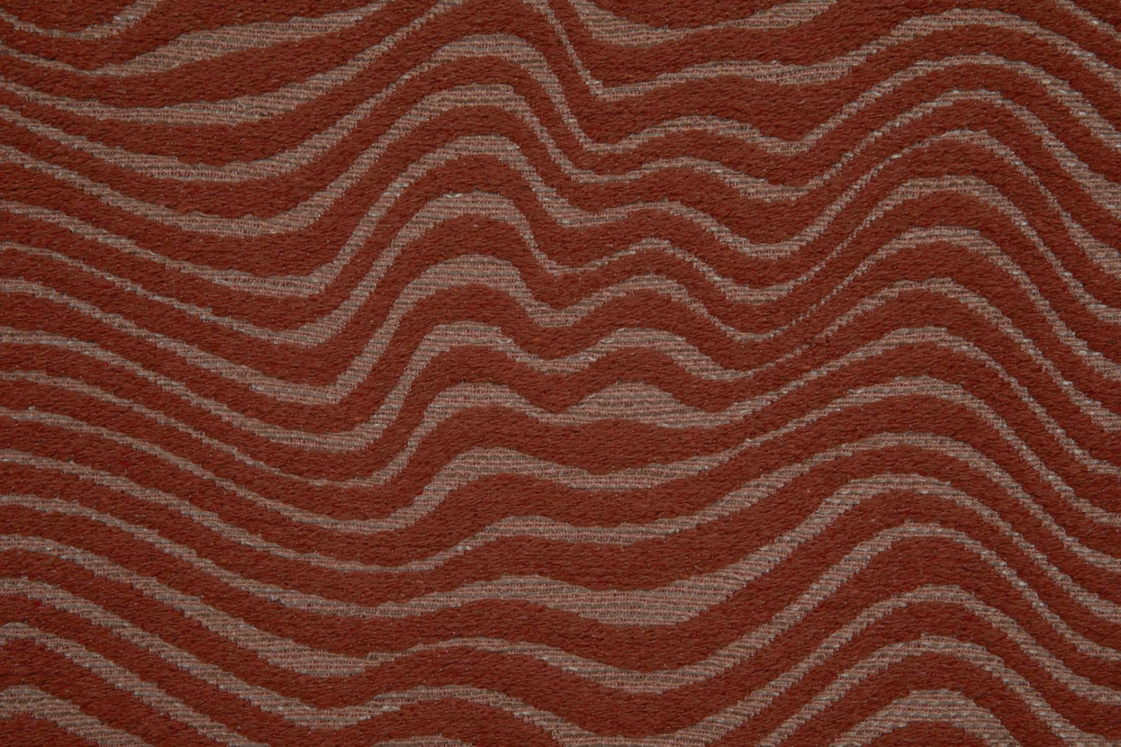 Rust terracotta textile with taupe-grey undulating lines and a tactile woven surface