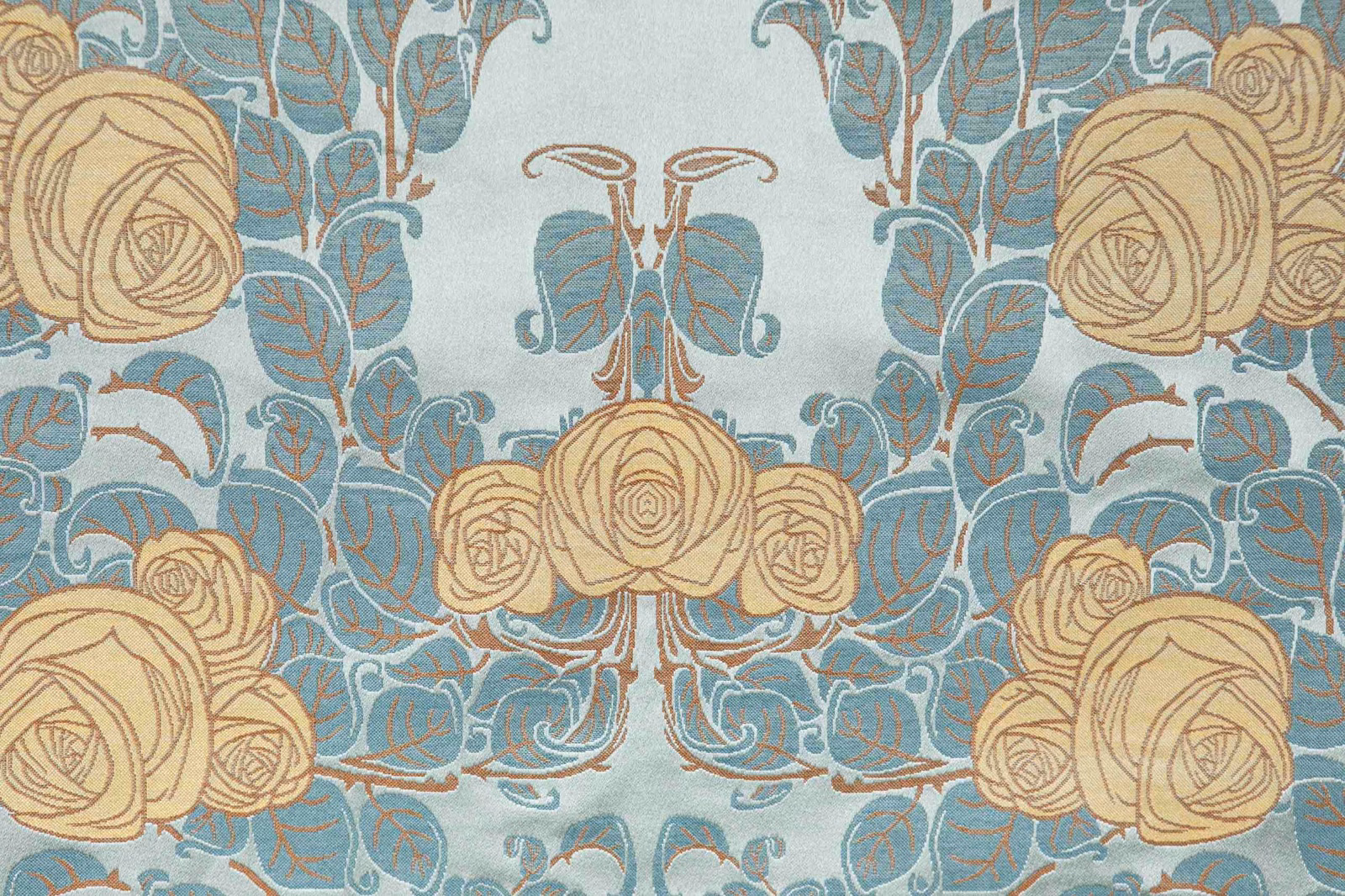Celadon floral fabric with blue foliage and beige roses in a symmetrical repeat