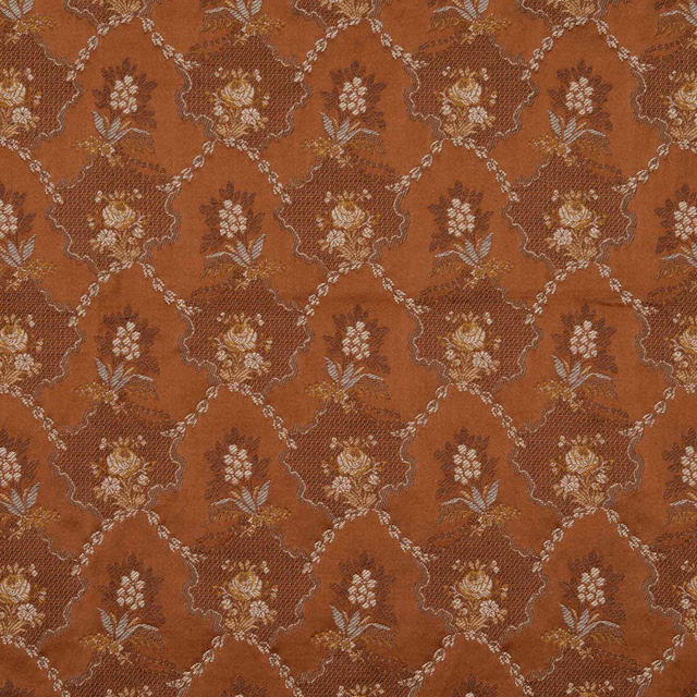 Rust terracotta fabric with cream floral sprays inside a scrolling lattice repeat