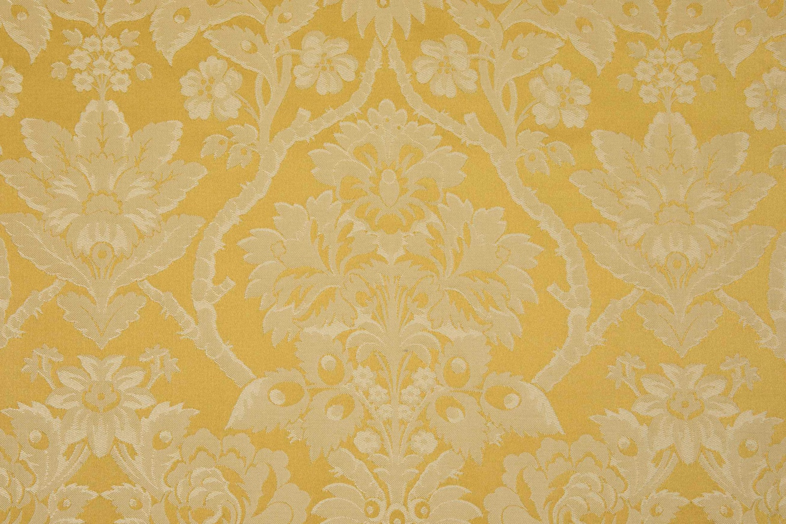 Warm ochre-gold damask with ivory flowers, scrolling foliage and woven texture
