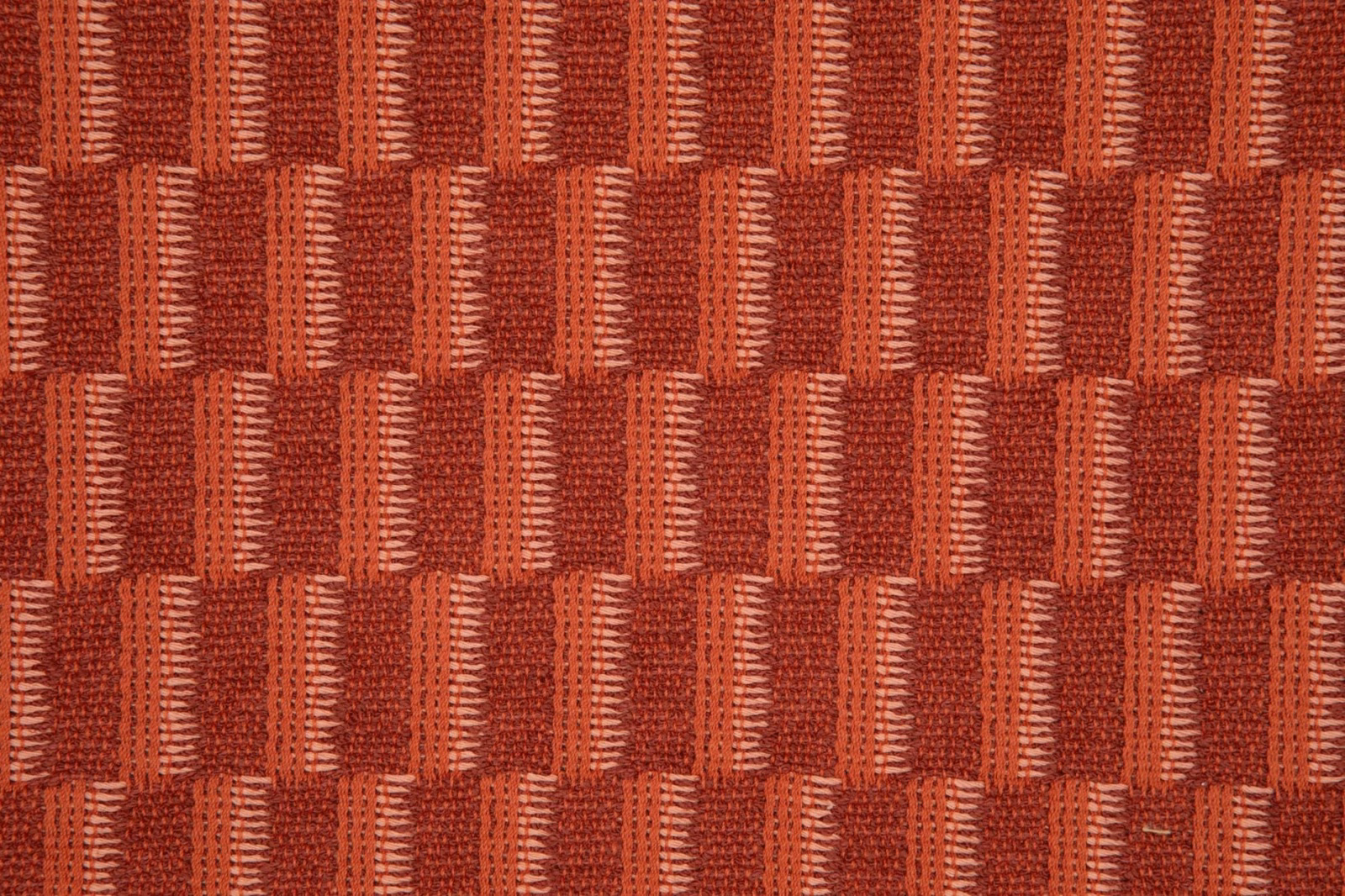 Deep terracotta woven fabric with staggered red blocks and ribbed vertical texture