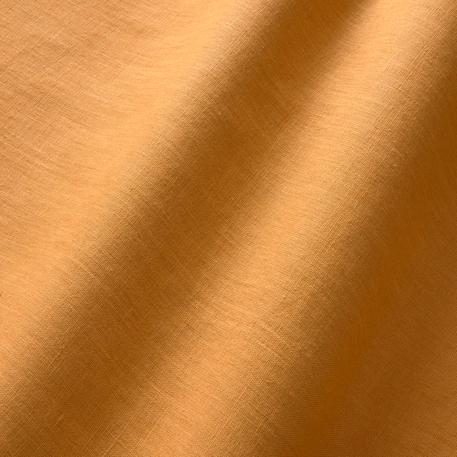 Burnt orange linen showing a fine plain weave and deep folded tonal shading