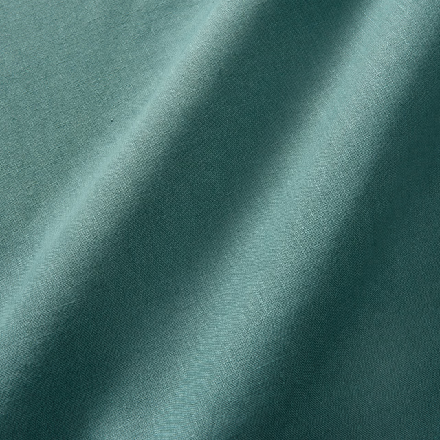 Sea-green plain linen showing fine weave and tonal folds from aqua to deep teal