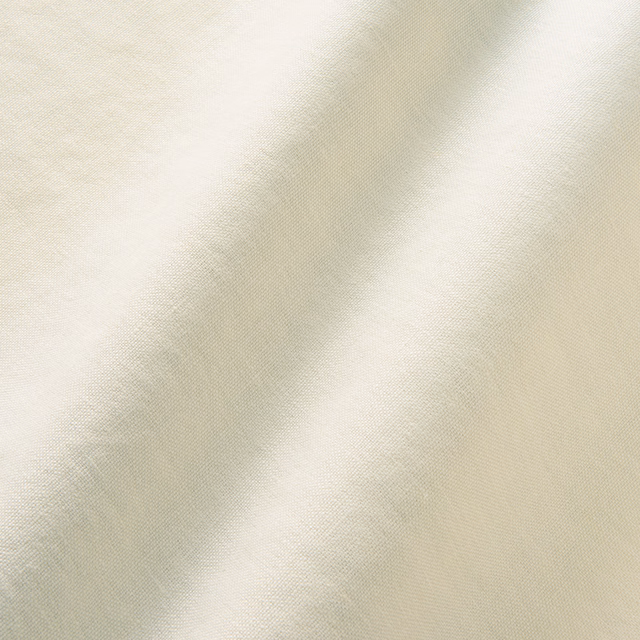 Close-up of warm ivory linen with fine diagonal weave and soft tonal variation