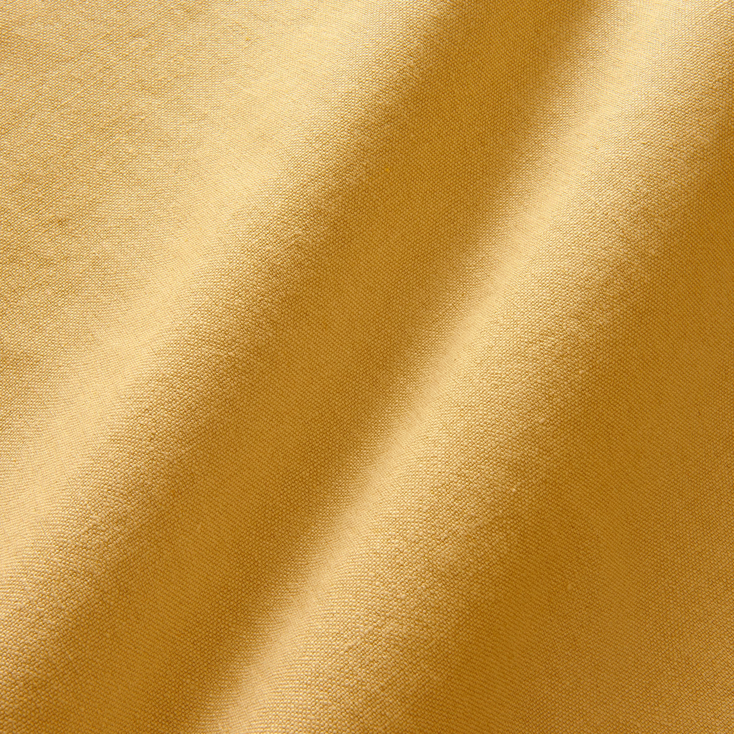 Close-up of warm maize-gold linen with a fine plain weave and softly shaded folds