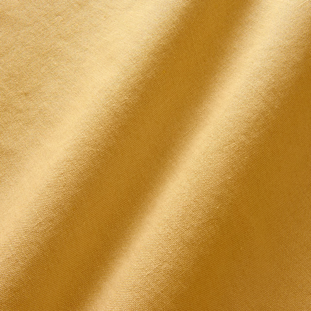 Close-up of warm maize-gold linen with a fine plain weave and softly shaded folds
