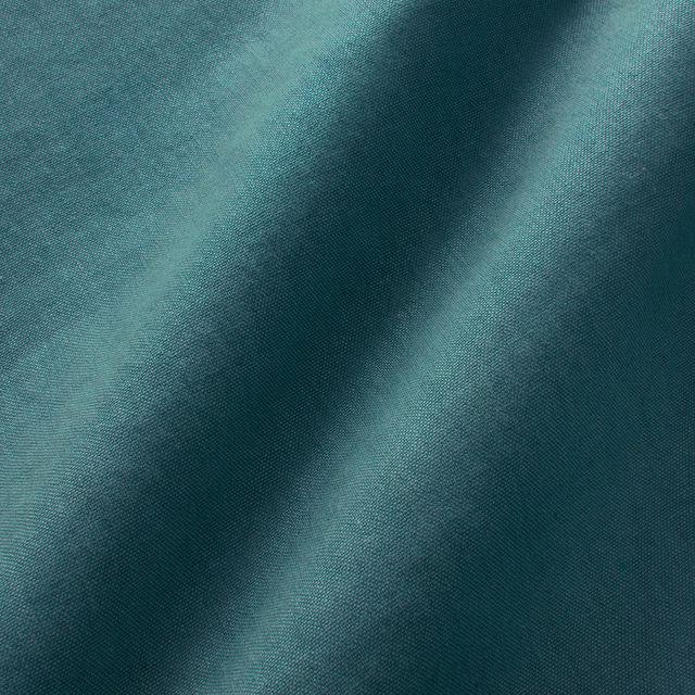 Deep petrol teal linen close-up showing fine weave and softly shifting folded highlights