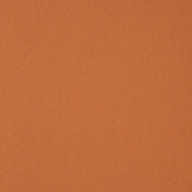 Close-up of warm apricot terracotta plain weave with subtly mottled wool texture