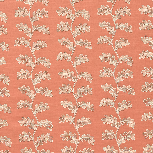 Coral pink woven fabric with ivory trailing leaf motif and subtle slub texture