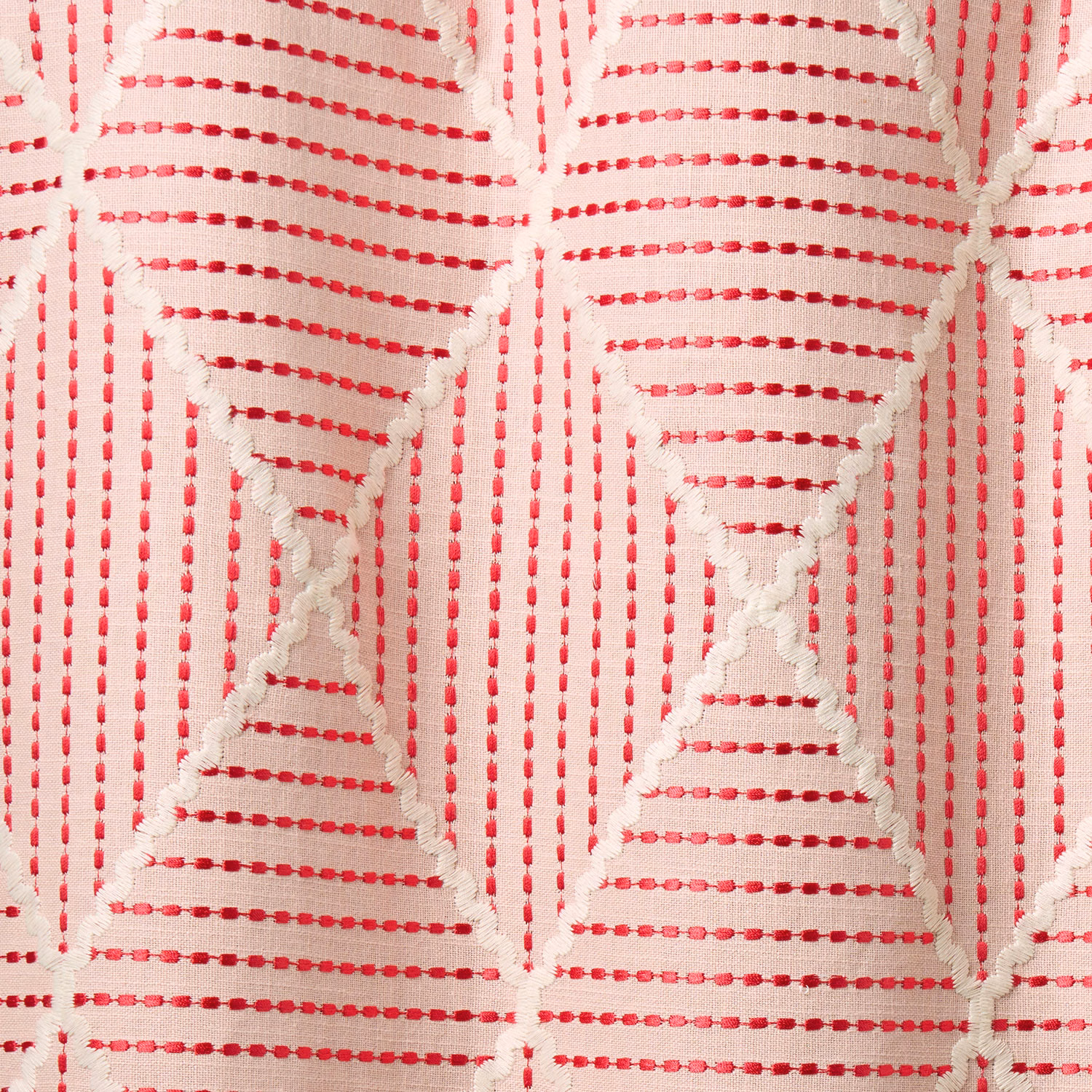 Close-up of strawberry pink geometric woven fabric on a pale ground