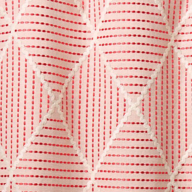 Close-up of strawberry pink geometric woven fabric on a pale ground