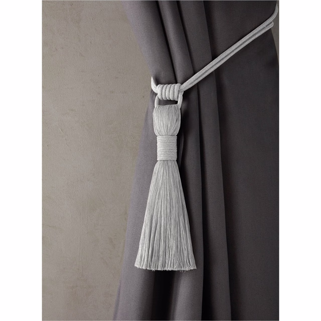Deep dove-grey curtain folds with a pale ribbed tassel tieback