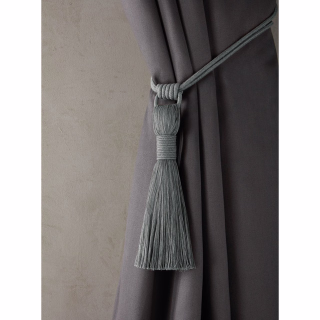 Deep charcoal-grey plain curtain fabric in full pleats with a grey tassel tie back