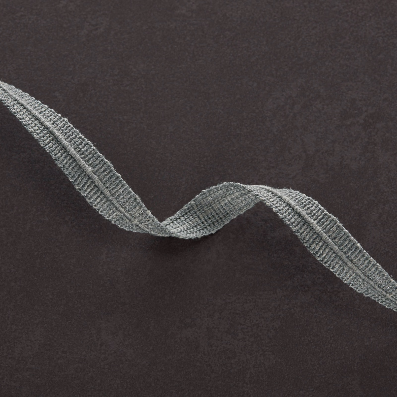Charcoal-brown textile with a raised blue-grey serpentine woven band
