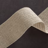 Warm natural beige ribbed textile with fine cross threads, folded to show its tactile texture