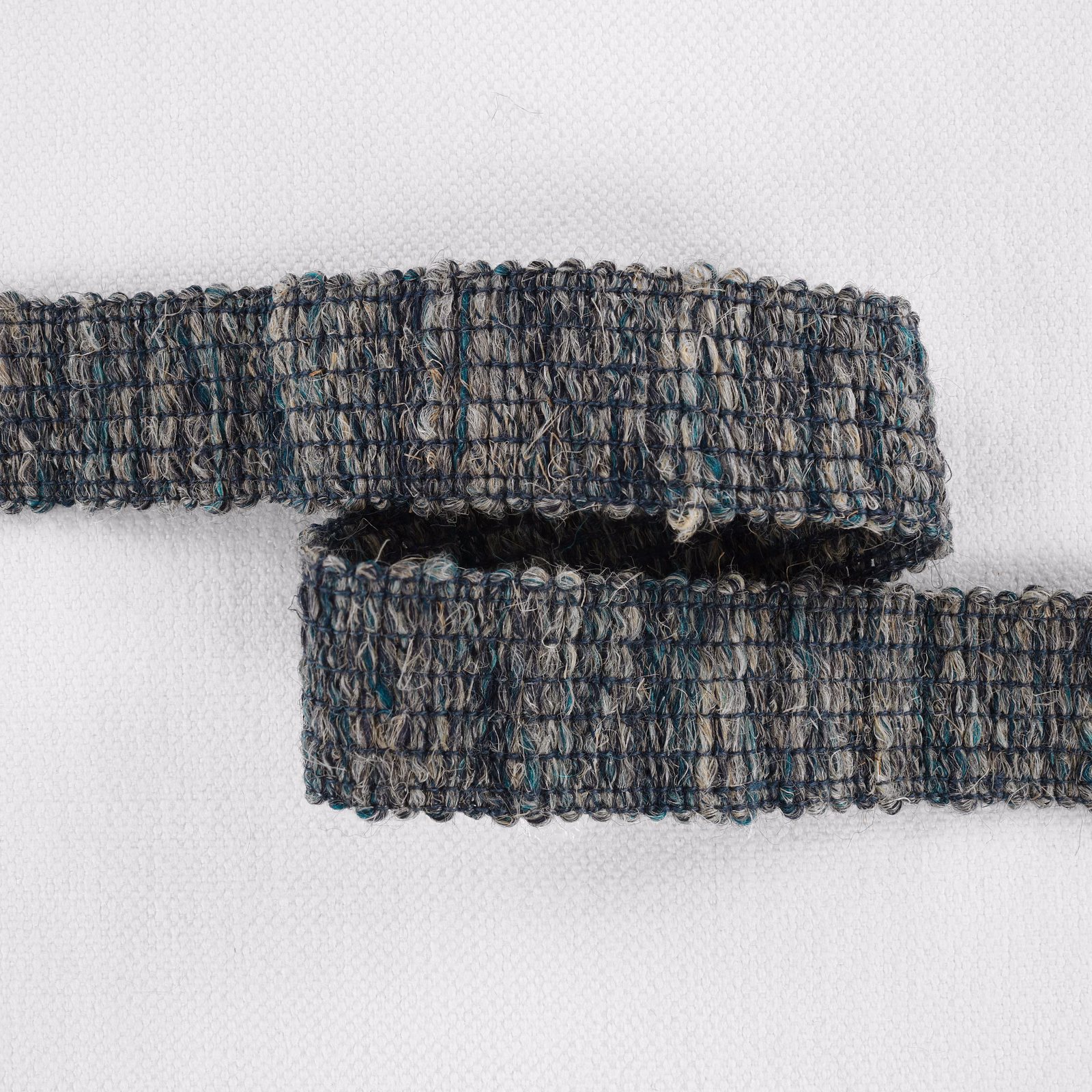 Overlapping muted teal, charcoal and taupe looped woven fabric bands on white