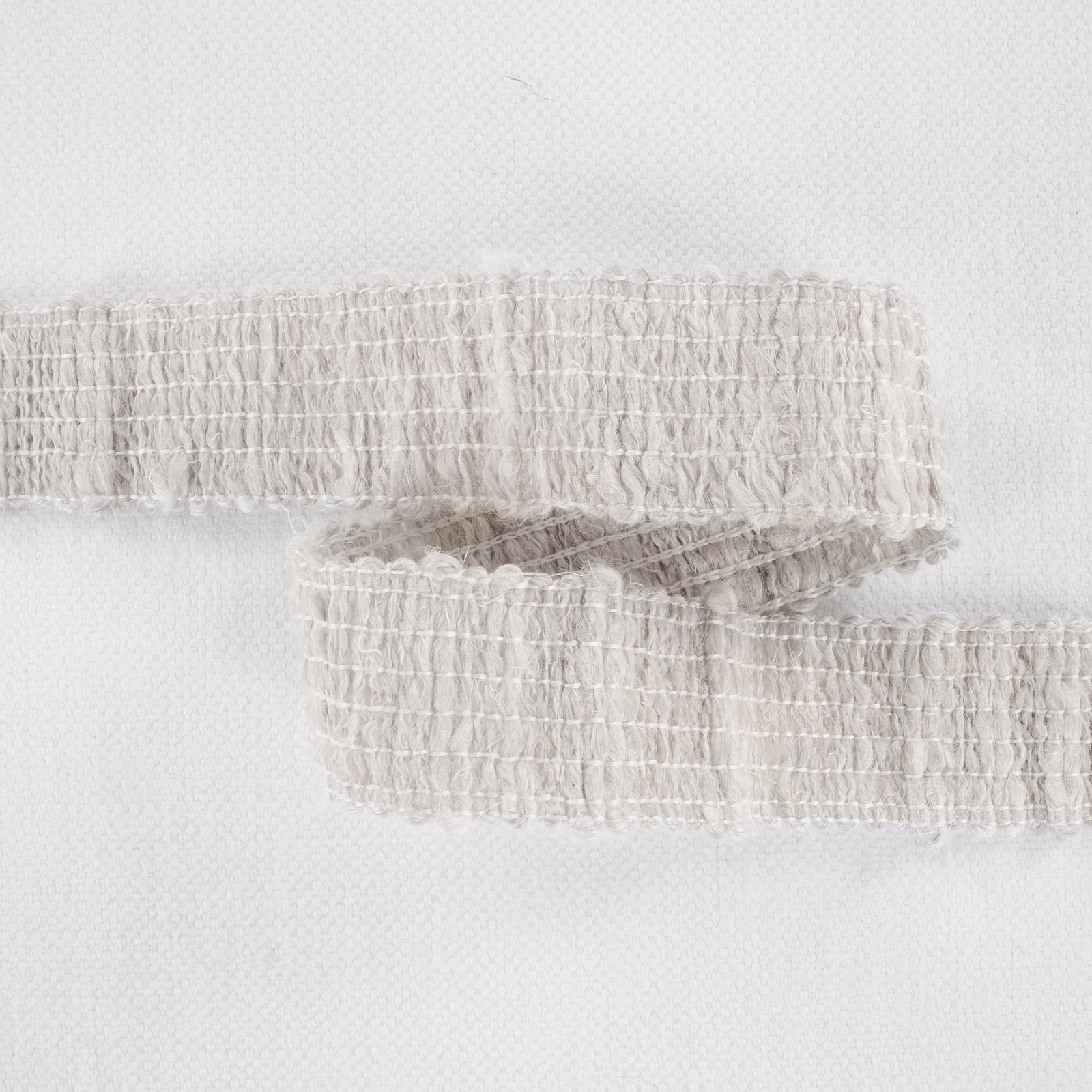 Pale plaster-ivory fabric with irregular looped ridges and softly fringed woven edges