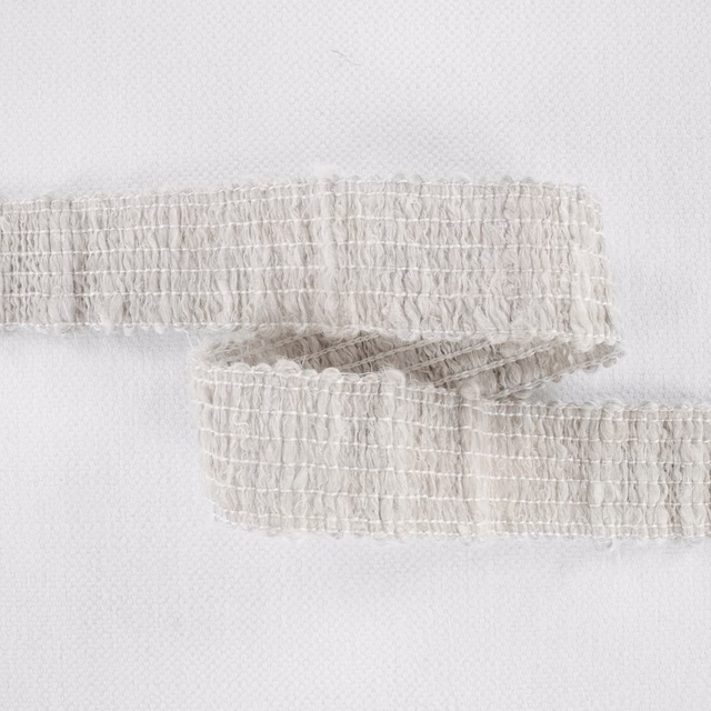 Pale plaster-ivory fabric with irregular looped ridges and softly fringed woven edges