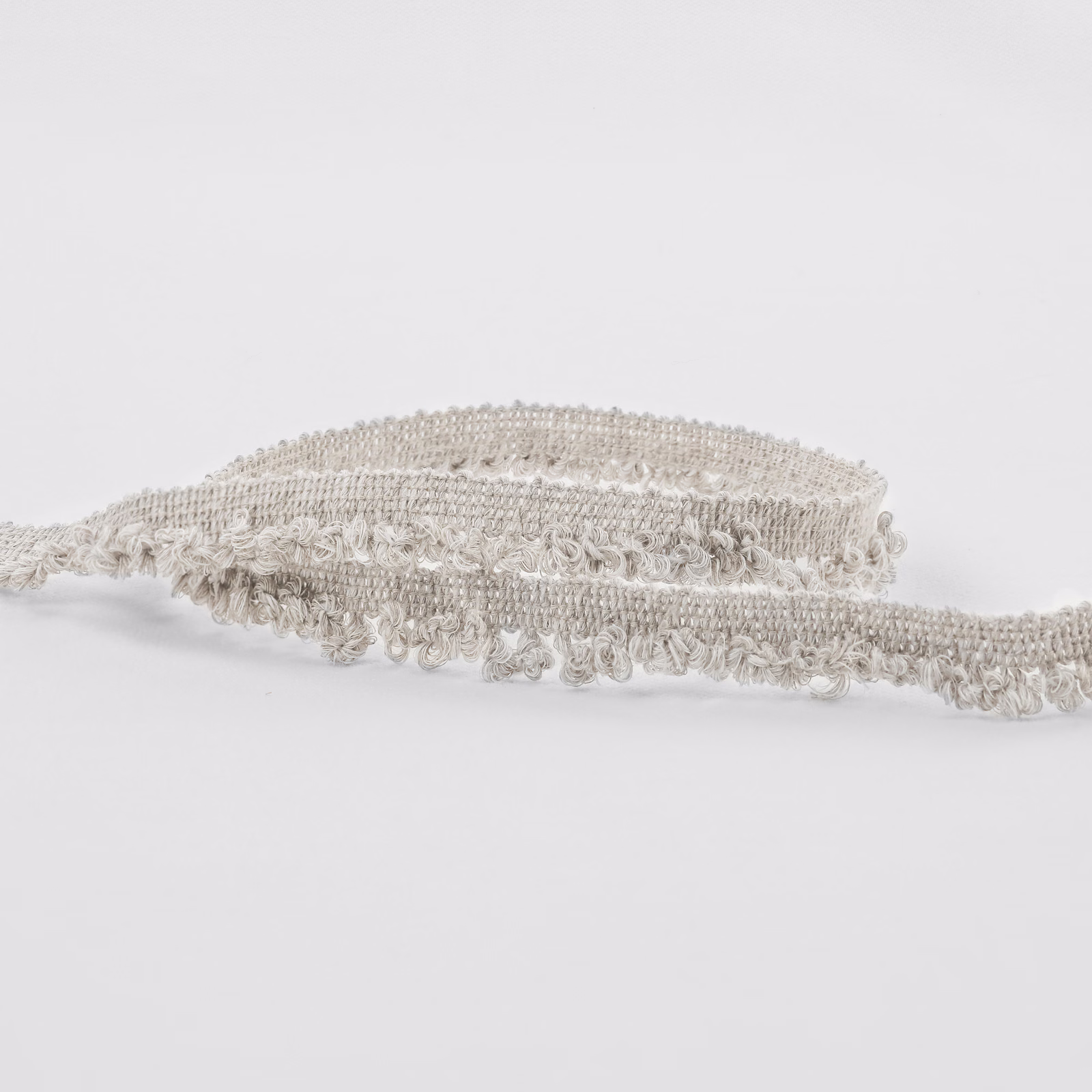 Warm ecru boucle fabric showing raised loops and a softly fringed woven edge