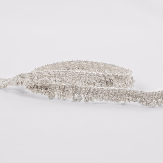 Warm ecru boucle fabric showing raised loops and a softly fringed woven edge