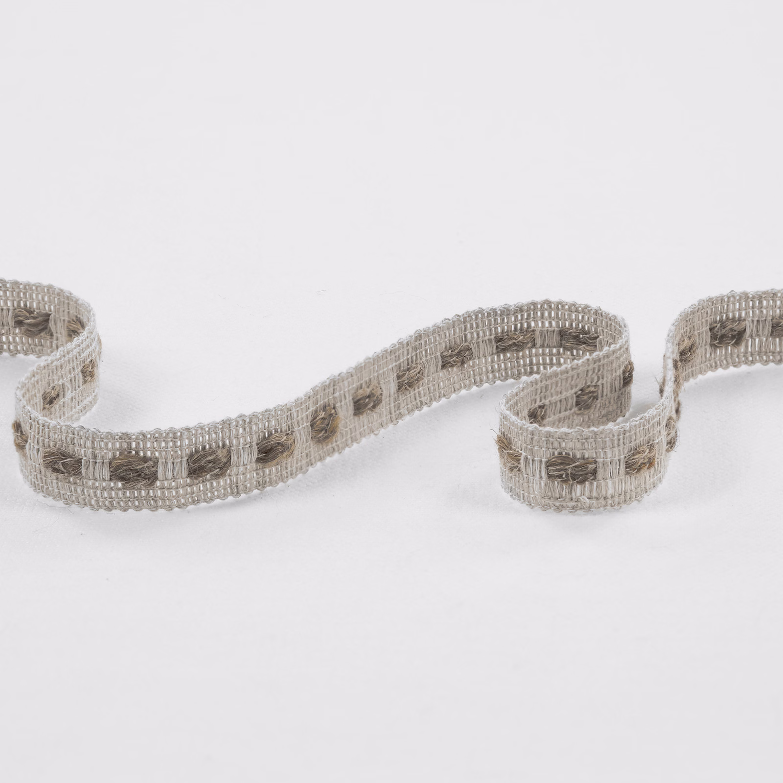 Taupe-grey open-grid fabric with repeating darker rectangular woven accents, curled into a strip
