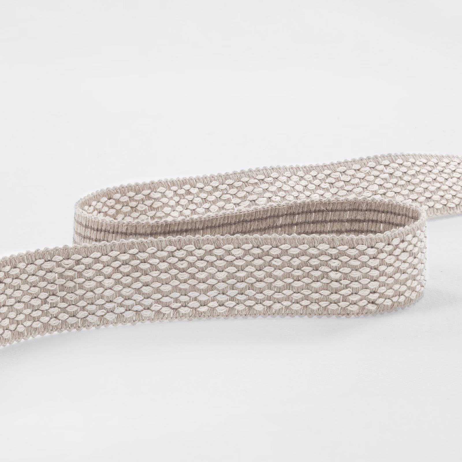 Pale taupe-grey woven fabric with small linked oval texture on a rolled strip