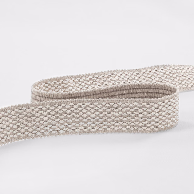 Pale taupe-grey woven fabric with small linked oval texture on a rolled strip