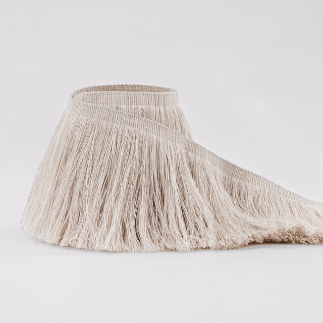 Warm ecru fringe fabric with long softly brushed strands catching the light