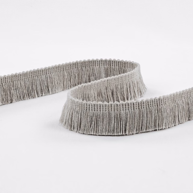 Cool cement-grey fringe trim with dense vertical strands looped across a white surface