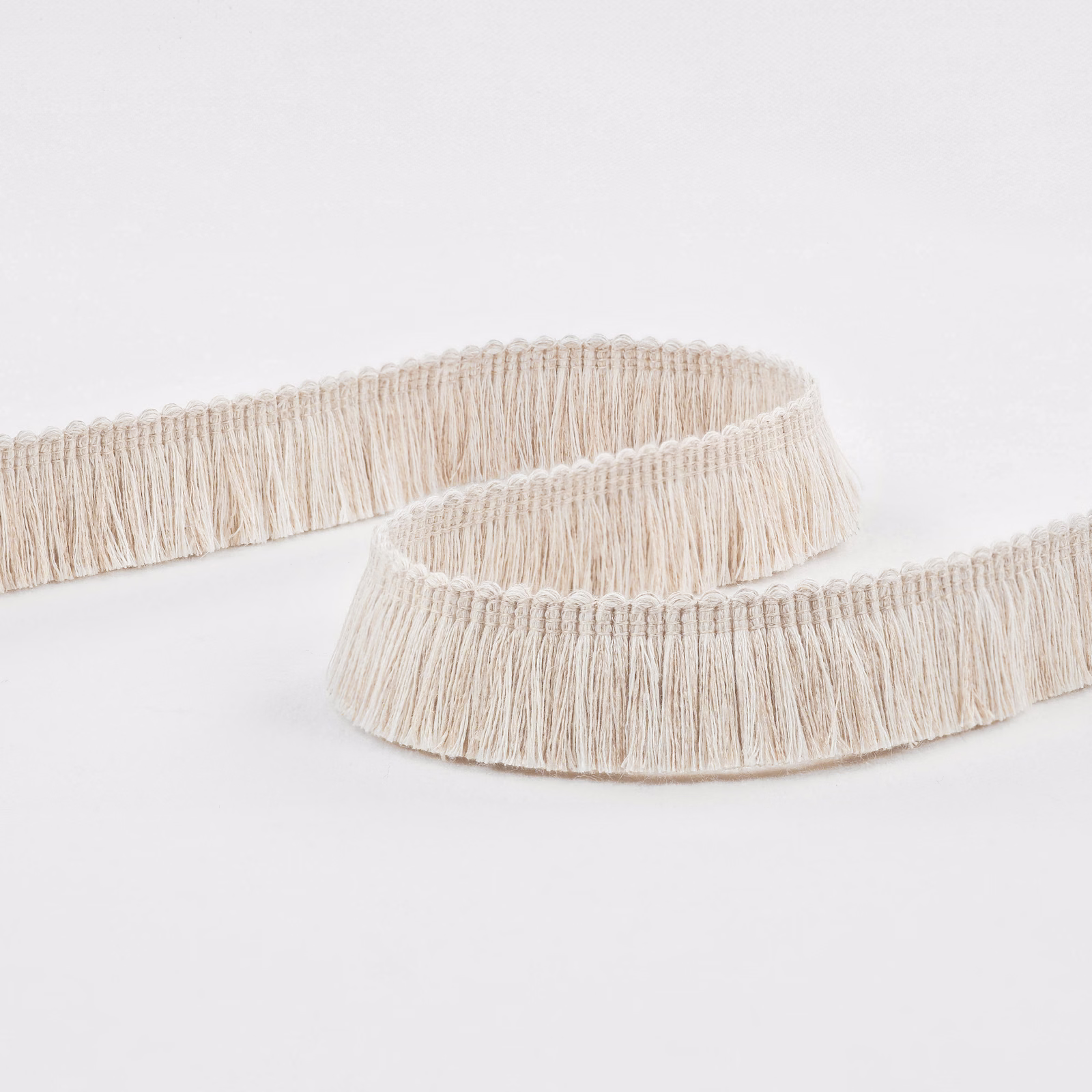 Warm ecru fringe trim with fine hanging strands and a looped header
