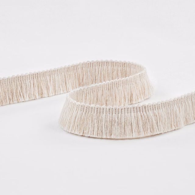 Warm ecru fringe trim with fine hanging strands and a looped header