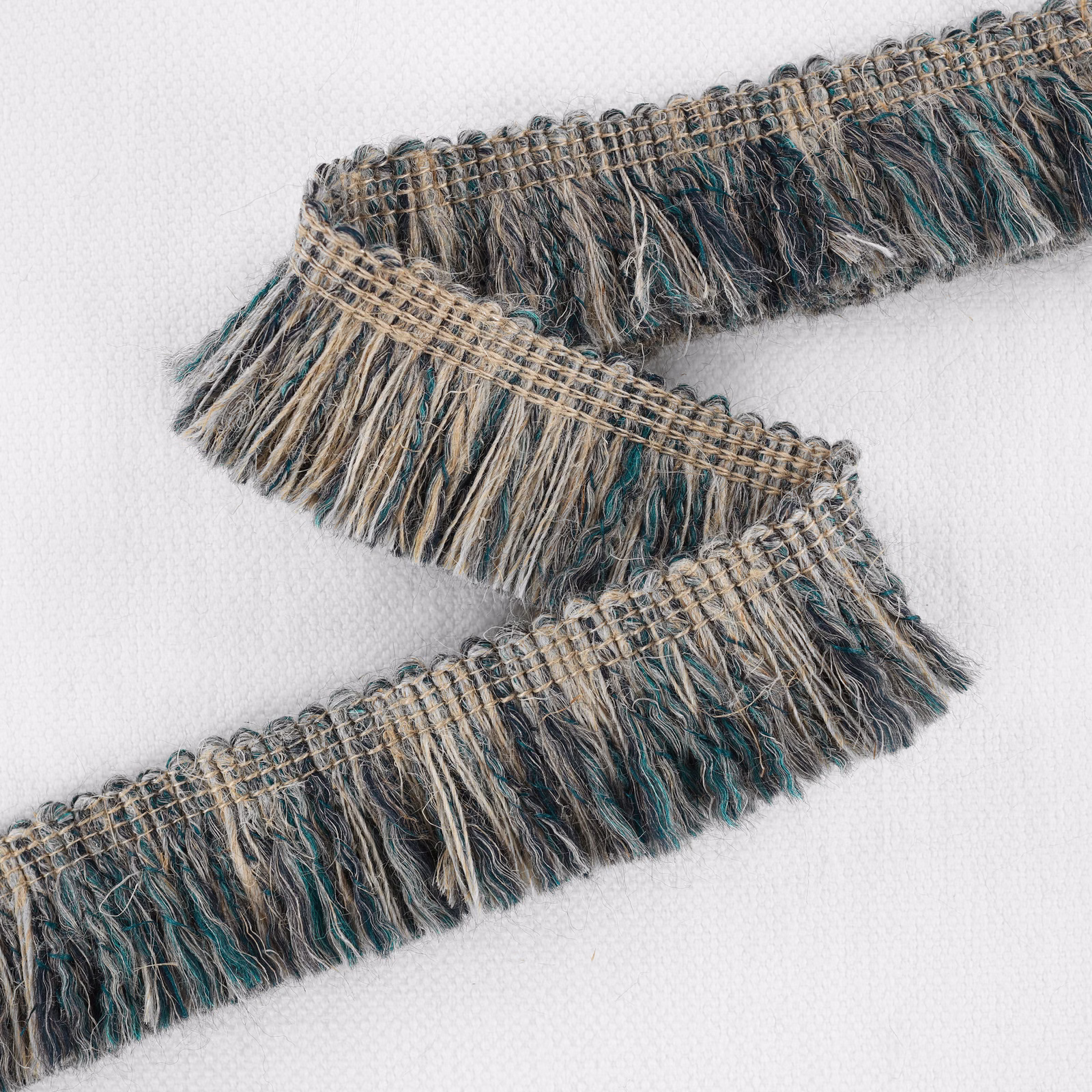 Close-up of muted ottanio teal, taupe and charcoal woven fringe with loose textured yarns