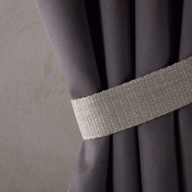 Cool cement-grey woven band with fine chevron texture beside charcoal curtain folds
