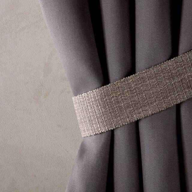Gunmetal-grey fabric falling in deep folds beside a coarse woven tie