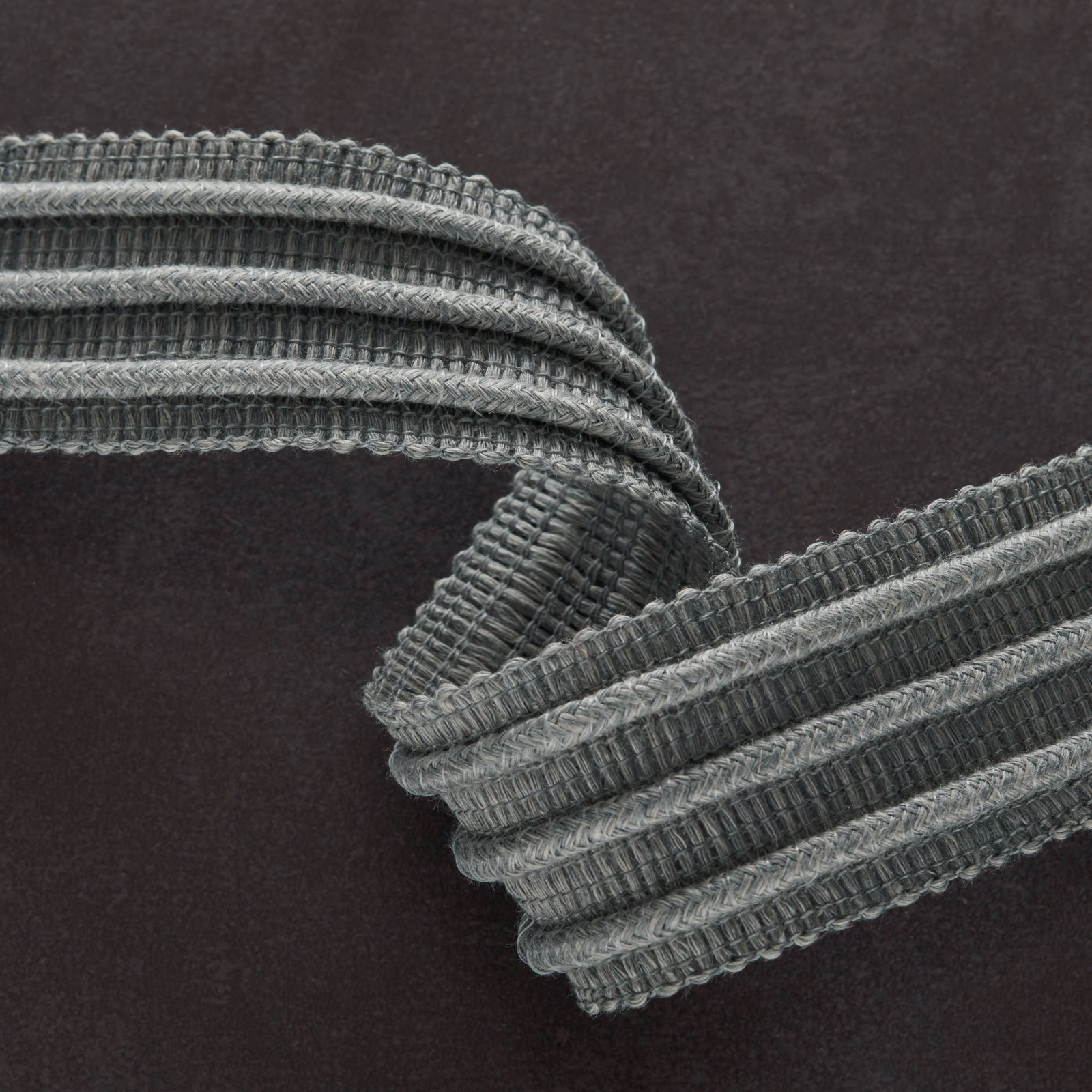 Deep charcoal grey textile with raised ribbed cords and lighter woven edges