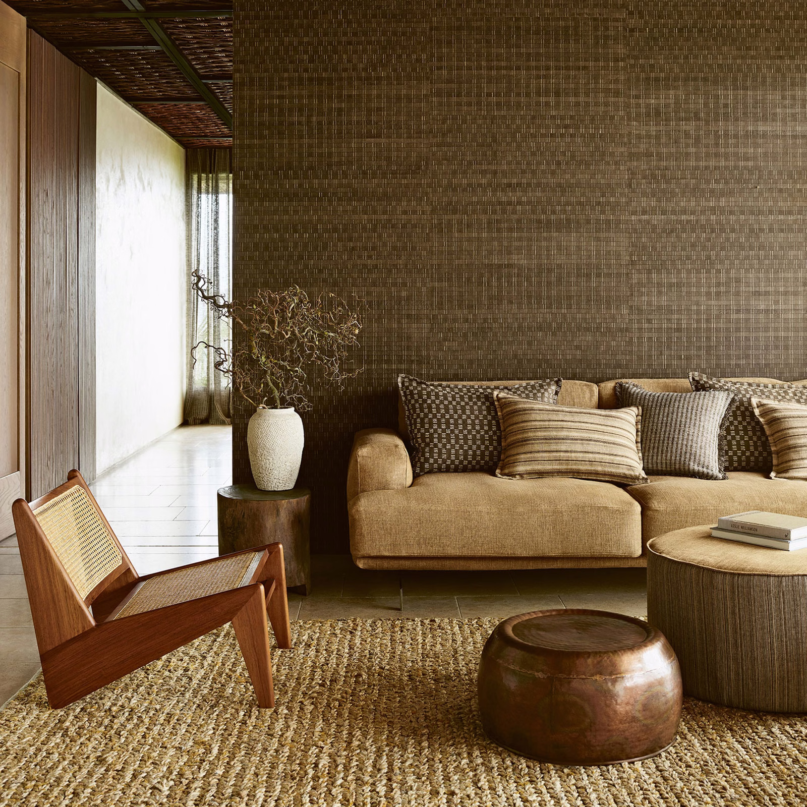 Warm chestnut wallpaper with a fine interlocking linear motif behind a tan sofa