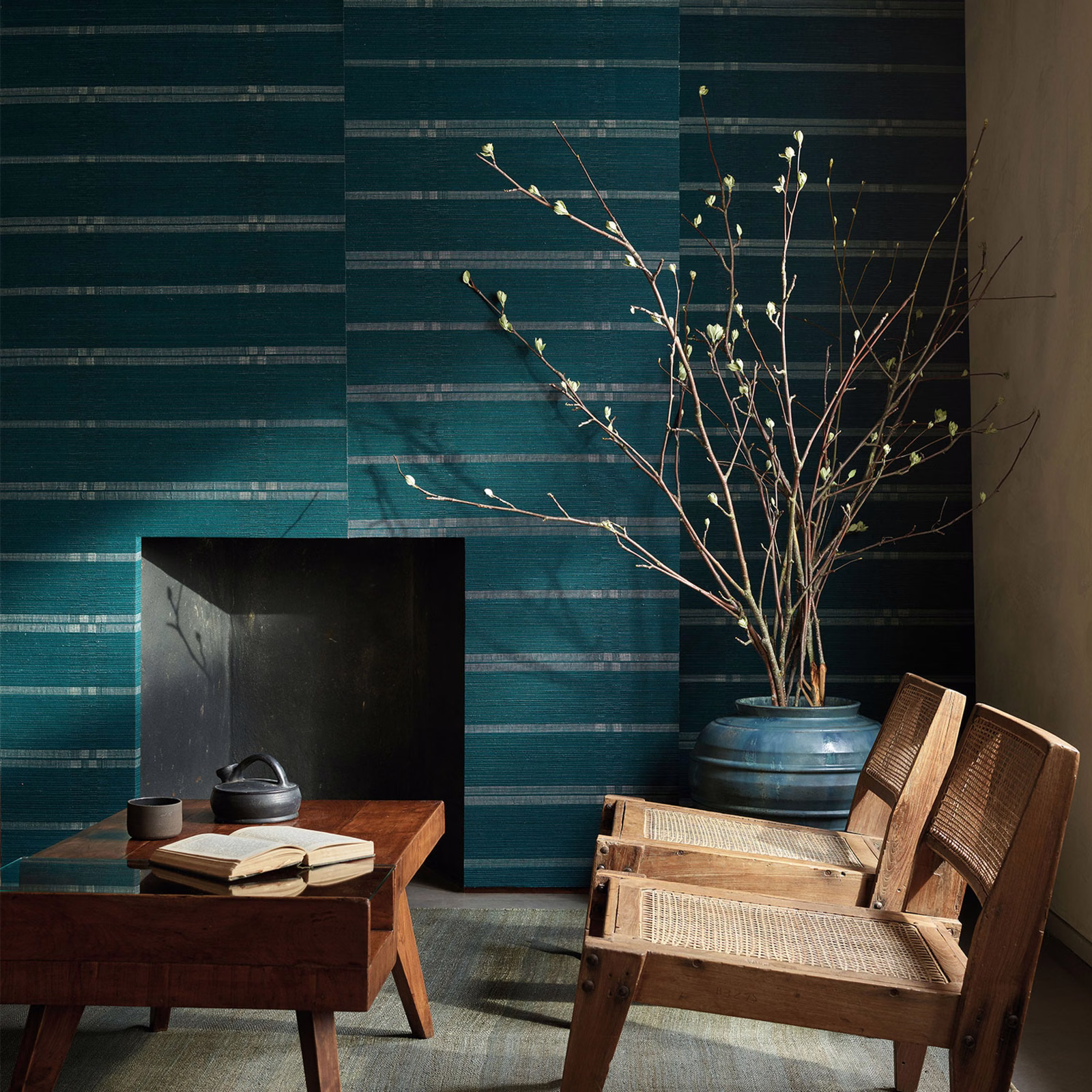 Deep peacock teal wallpaper with layered horizontal striations behind timber furniture