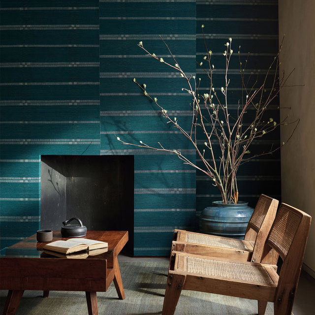 Deep peacock teal wallpaper with layered horizontal striations behind timber furniture