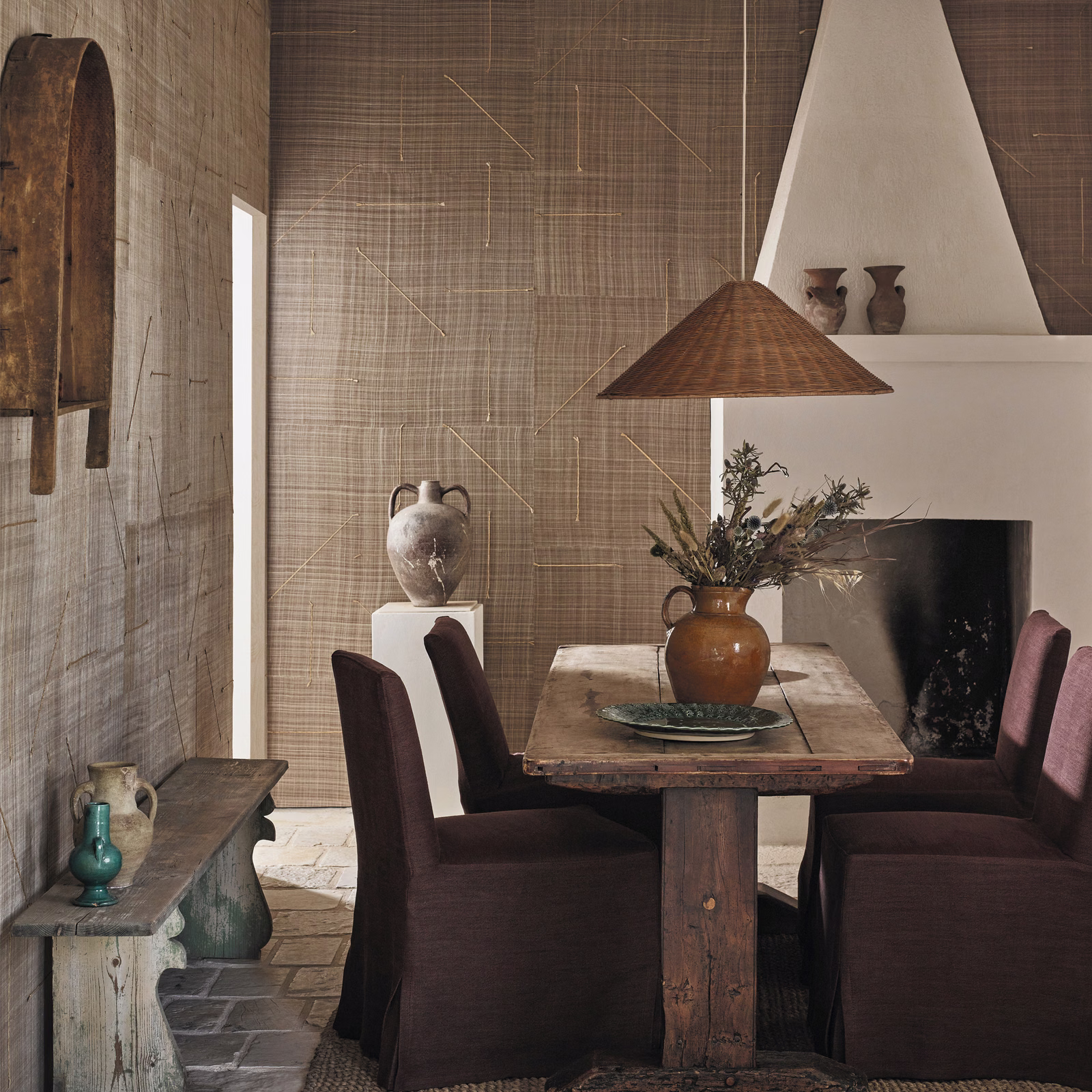 Warm clay-brown crosshatch wallcovering with sparse angular lines in a rustic dining room