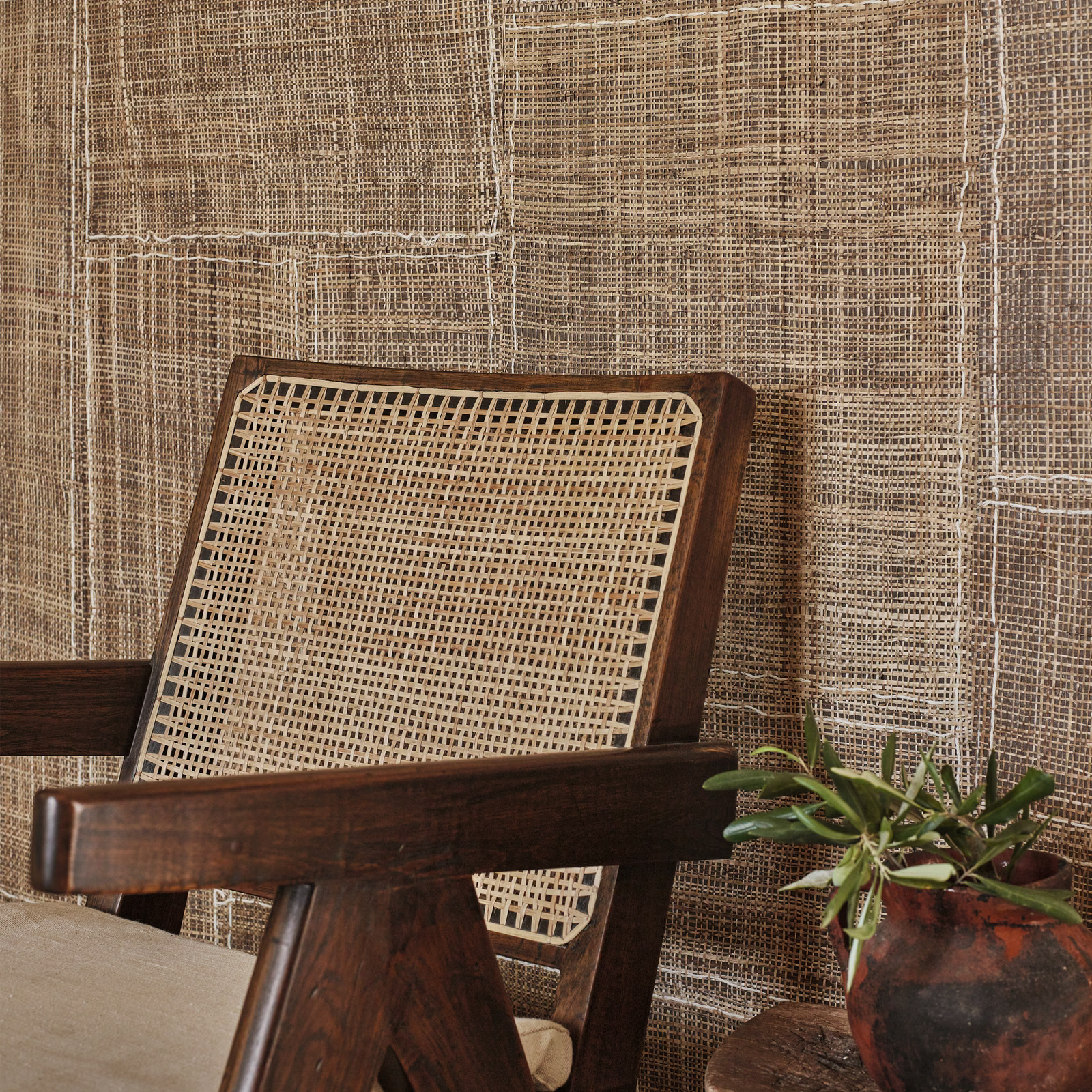 Warm chestnut wallpaper with an irregular woven grid behind a dark timber cane chair
