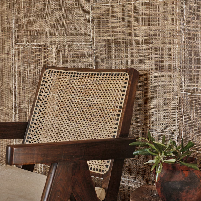 Warm chestnut wallpaper with an irregular woven grid behind a dark timber cane chair