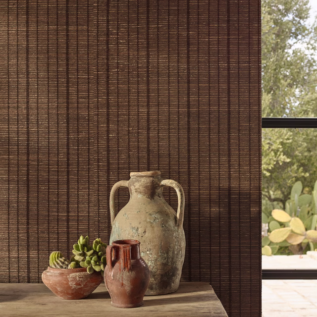 Deep paprika-brown wallcovering with fine dark vertical striations beside rustic pottery