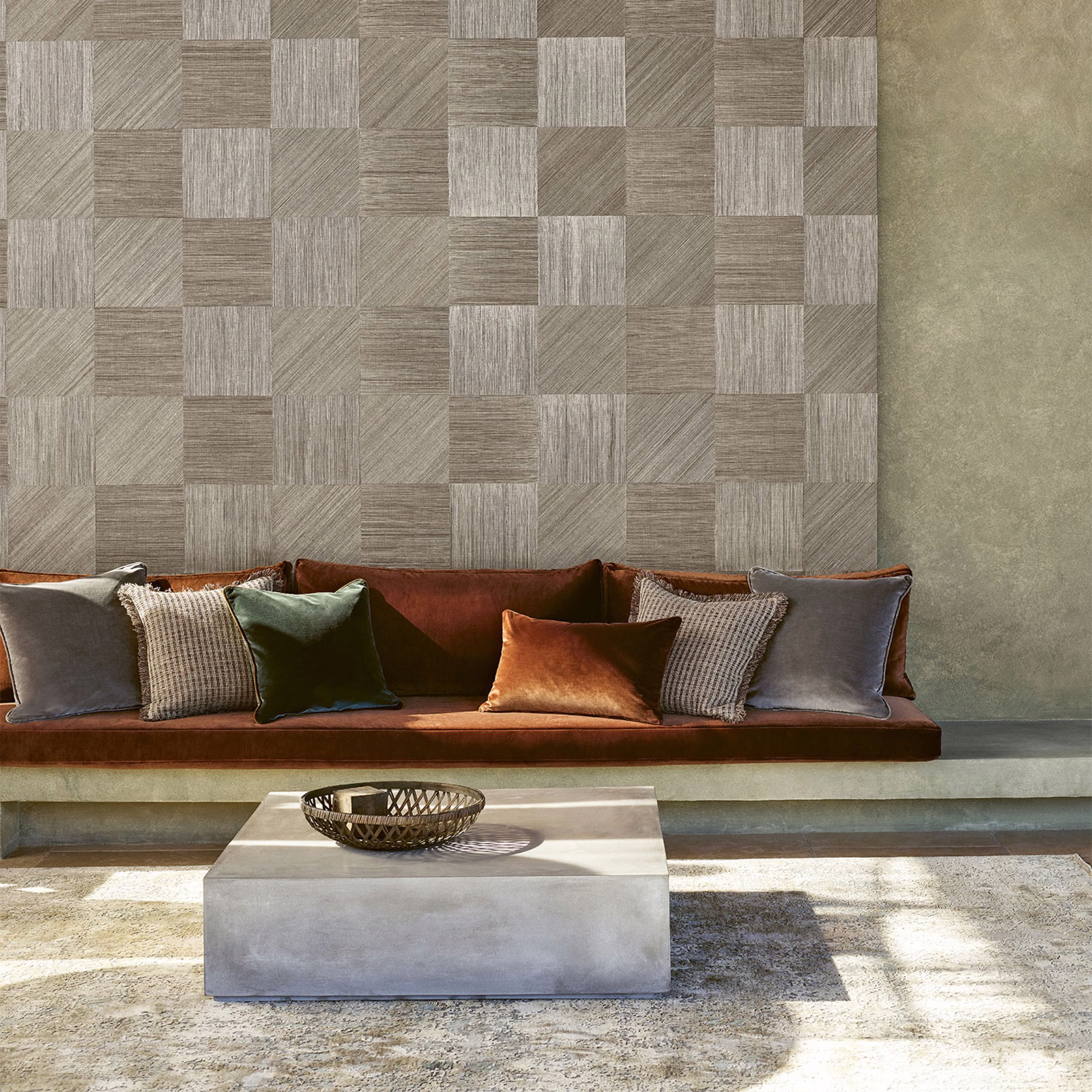 Silver grey geometric block wallpaper with varied linear textures behind a rust sofa