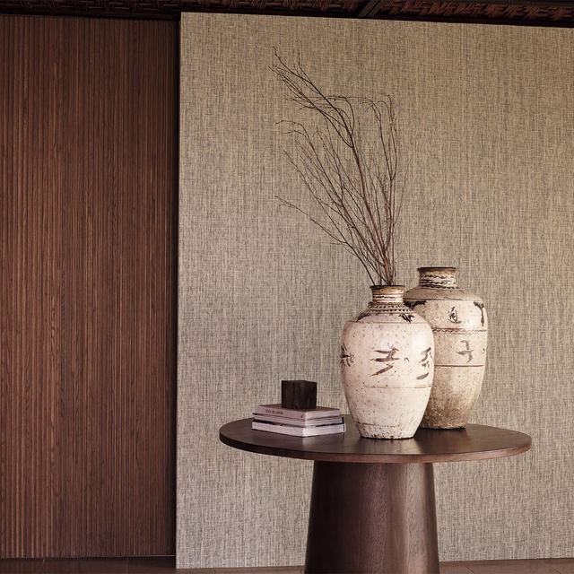 Muted taupe-grey wallpaper with fine vertical paperweave texture beside dark timber