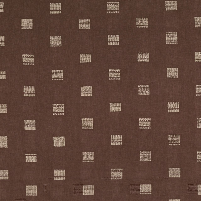 Sienna-brown woven fabric with scattered cream geometric block motifs and fine texture