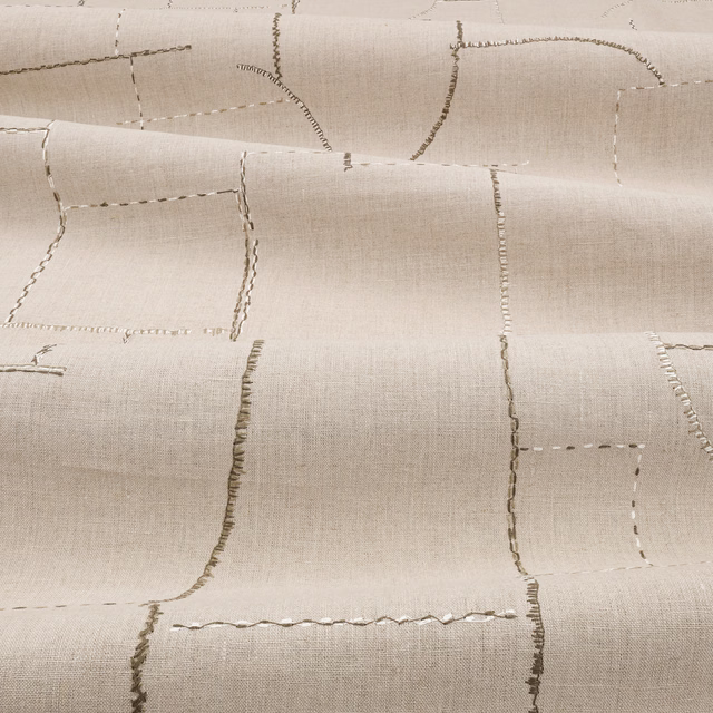 Warm flax-beige fabric with irregular embroidered rectangles and a fine woven surface