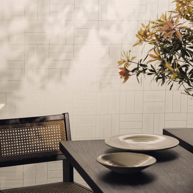 Warm ivory textile with fine irregular grid lines, photographed behind a dark dining table