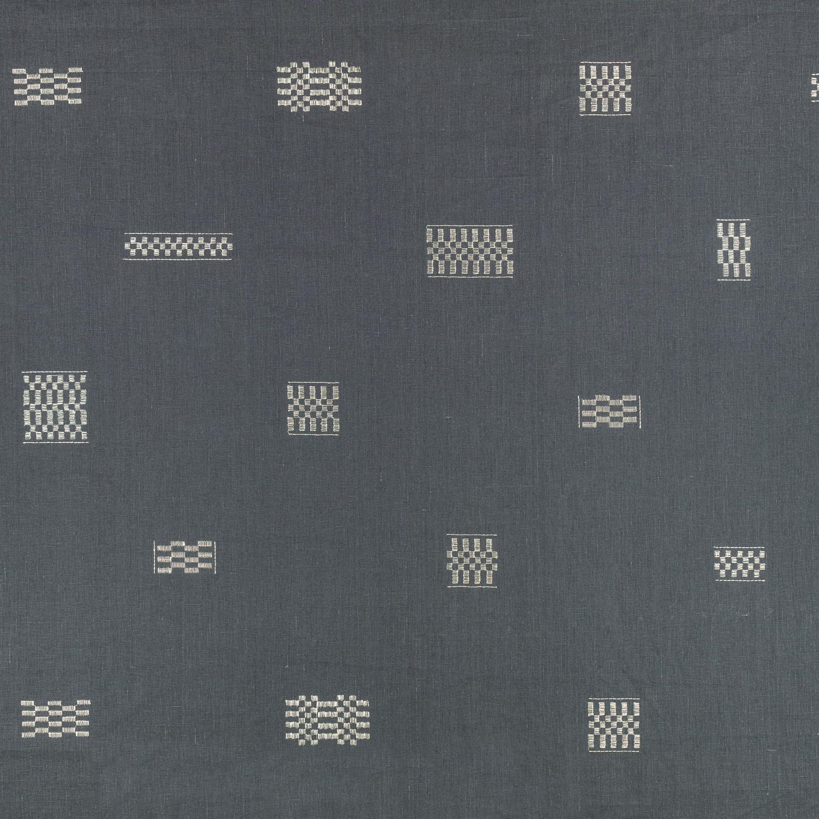 Blue-grey textile with scattered cream geometric embroidered motifs in varied small blocks